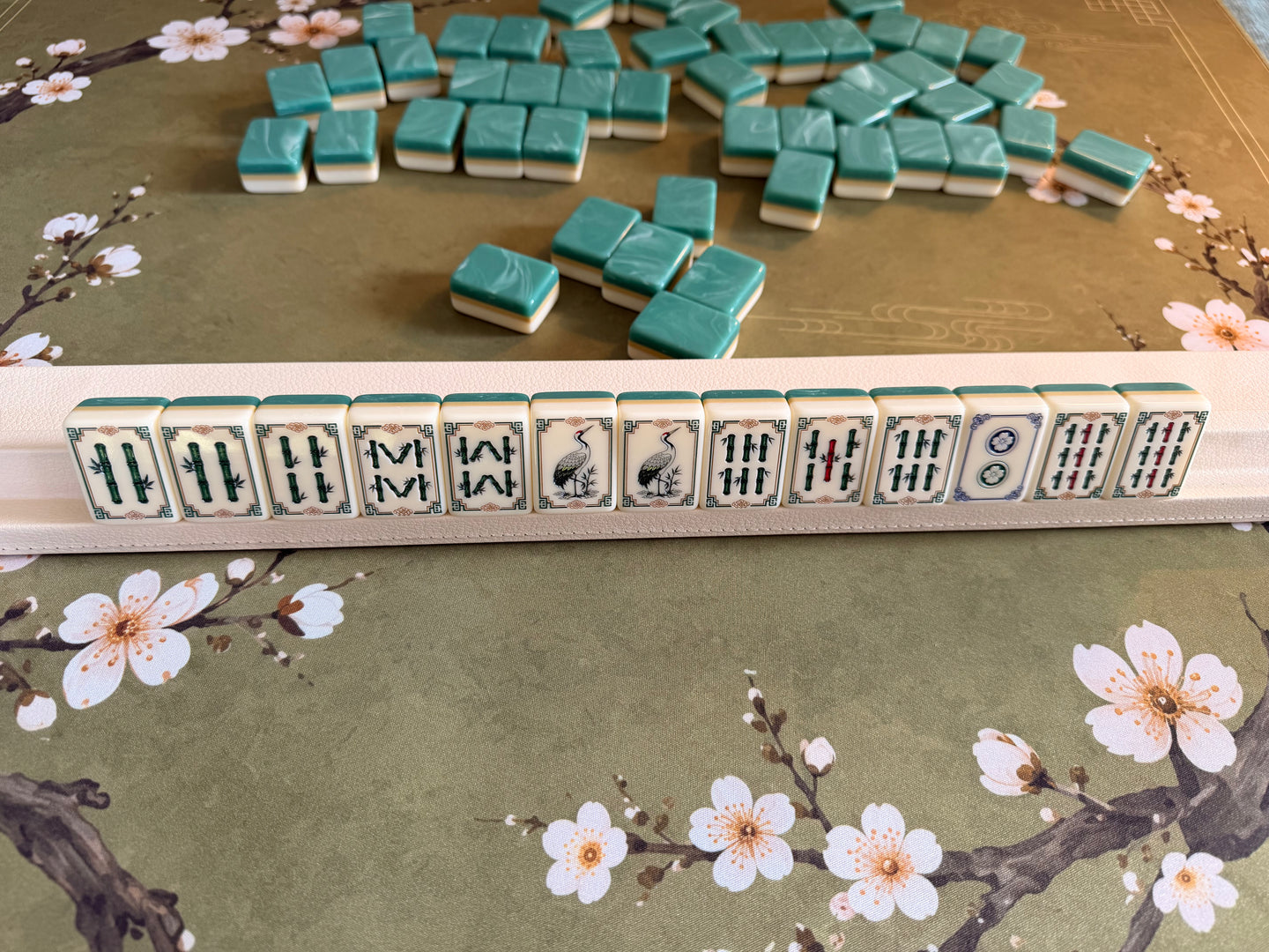 Pearl vegan leather Mahjong rack holding Jade Collection tiles on the Plum Blossom mat
